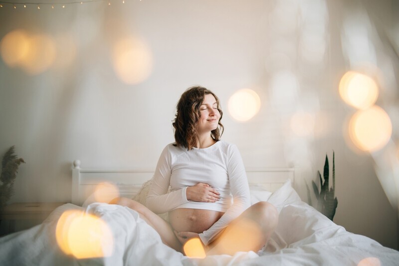  mulher grávida feliz de branco segurando a barriga