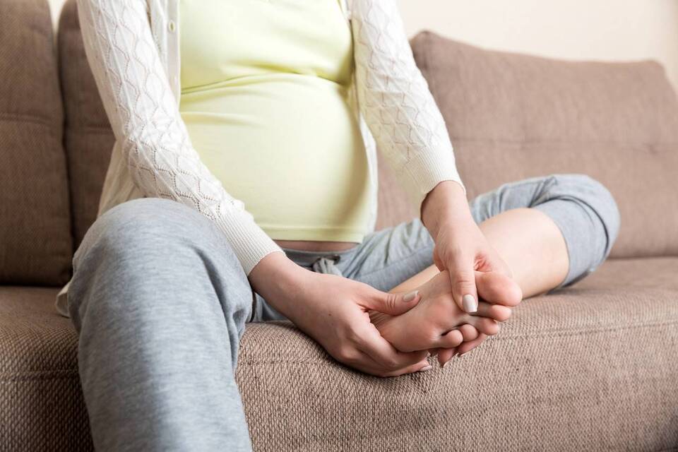 Mulher grávida massageando o pé