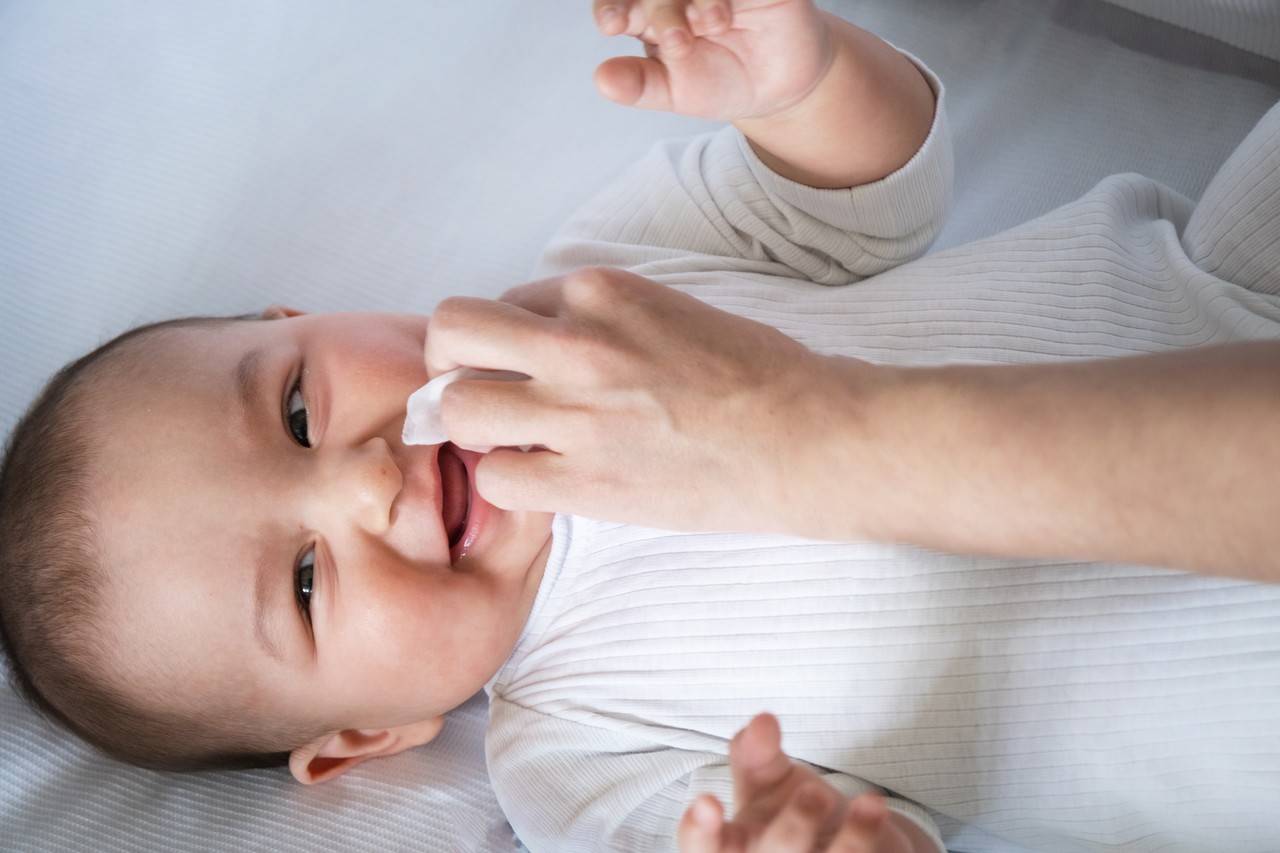 Bebê sorrindo enquanto mulher limpa seu rosto com lenço umedecido