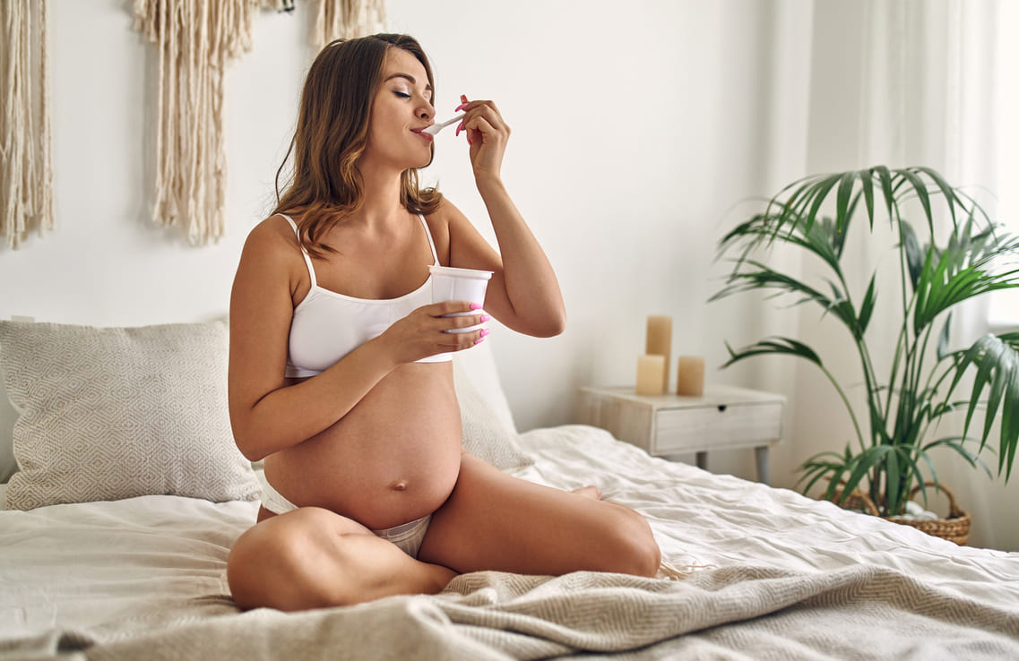 mulher grávida segue a dieta comendo iogurte 