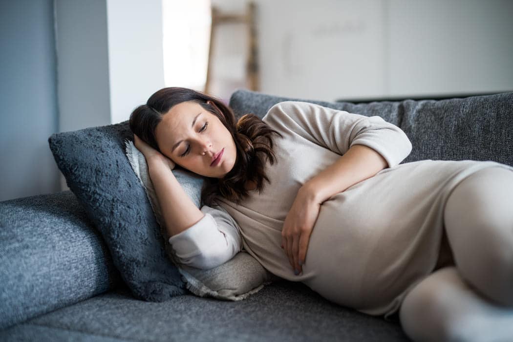 mulher grávida descansa deitada no sofá