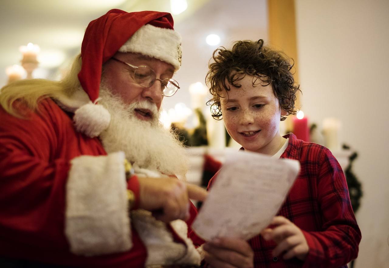 Papai Noel mostrando bilhete para criança