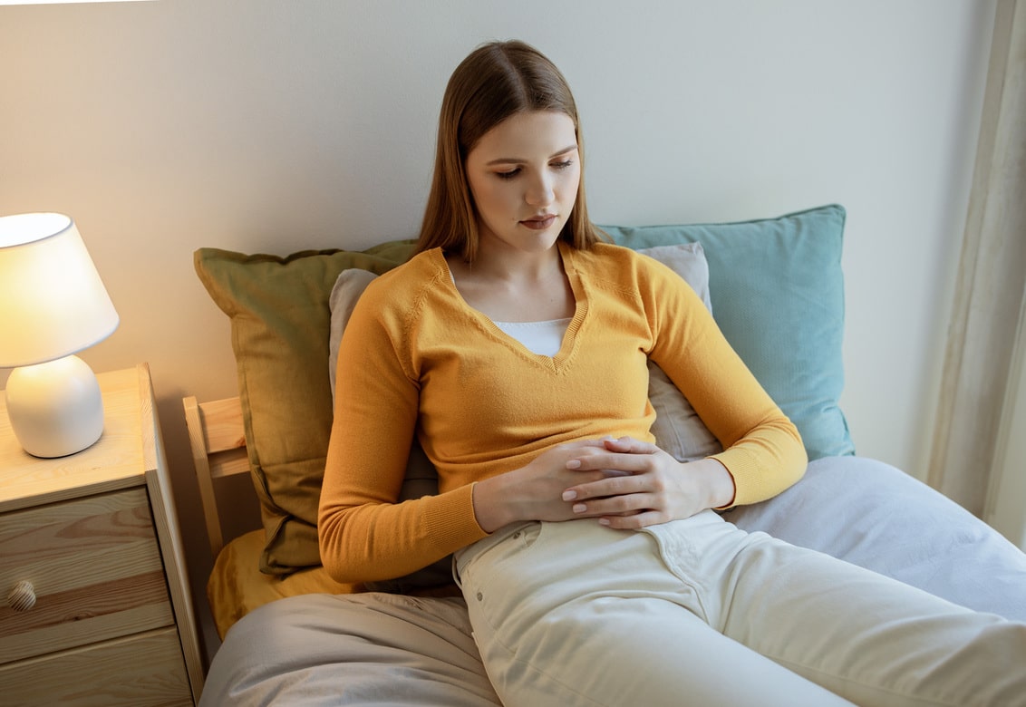 mulher com barriga de primeira semana de gravidez sentada na cama