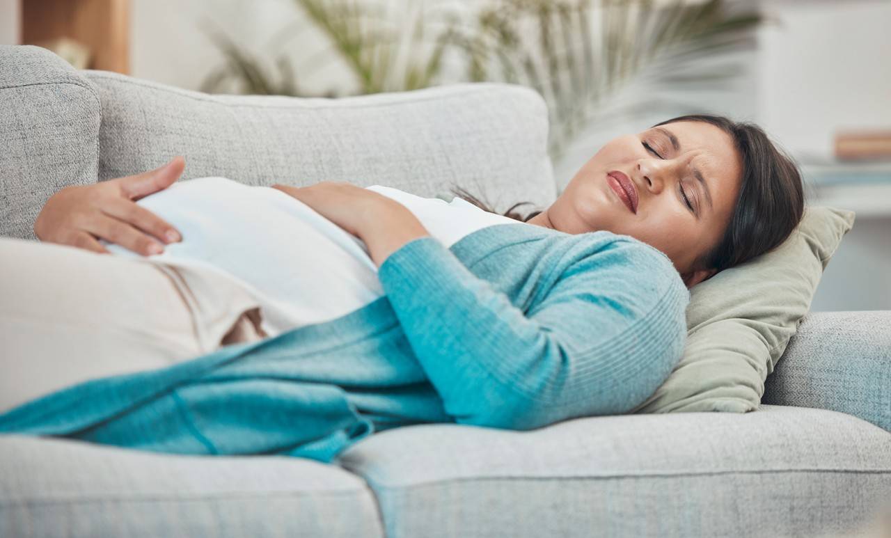 mulher com gravidez ectópica deitada no sofá de barriga para cima