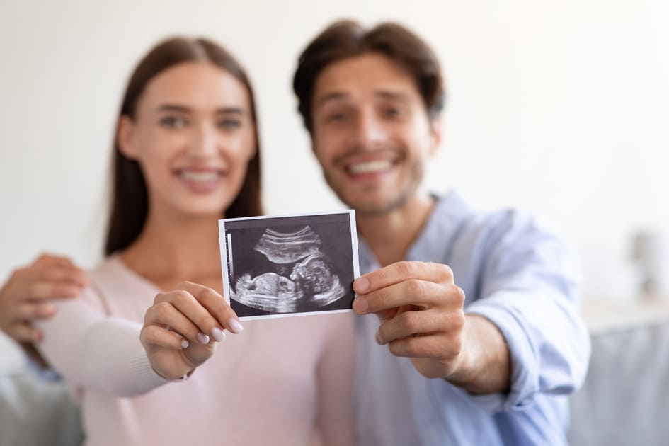 um casal jovem segurando a ultrassom de um bebê de 14 semanas