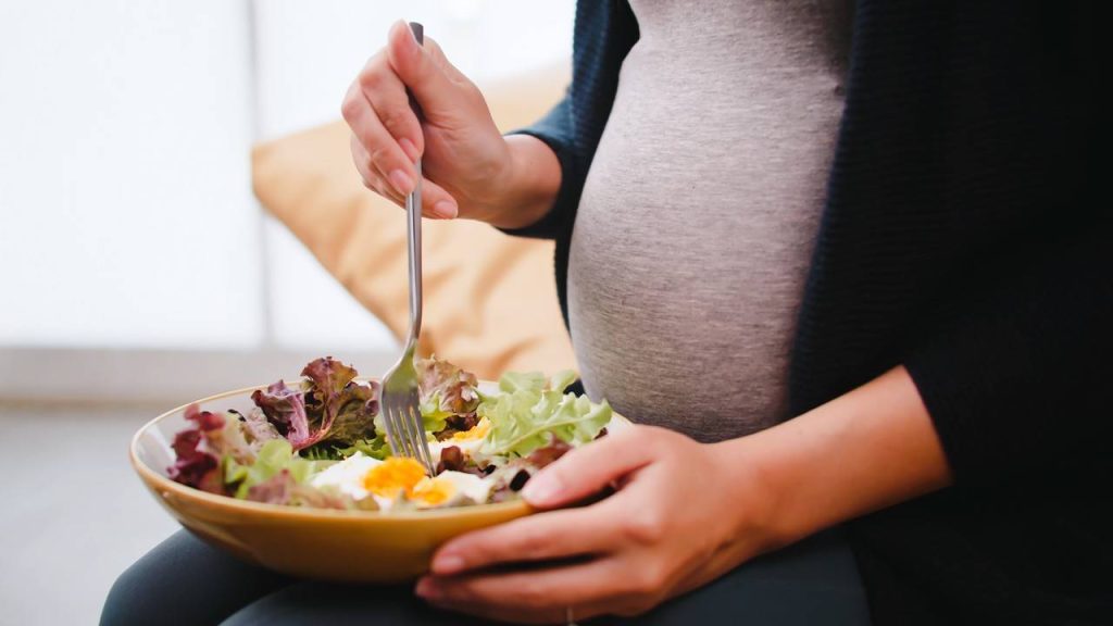 mulher grávida comendo um prato de salada
