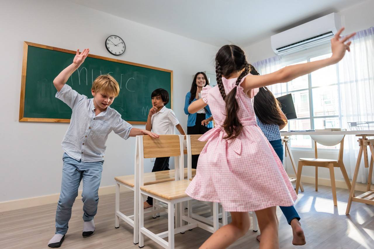 crianças em uma sala de aula brincando de dança das cadeiras