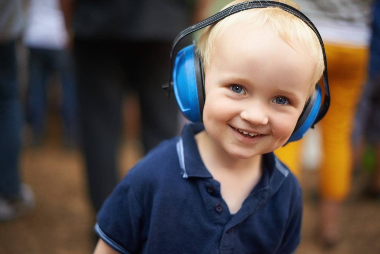 menino autista com um fone de ouvido azul na rua