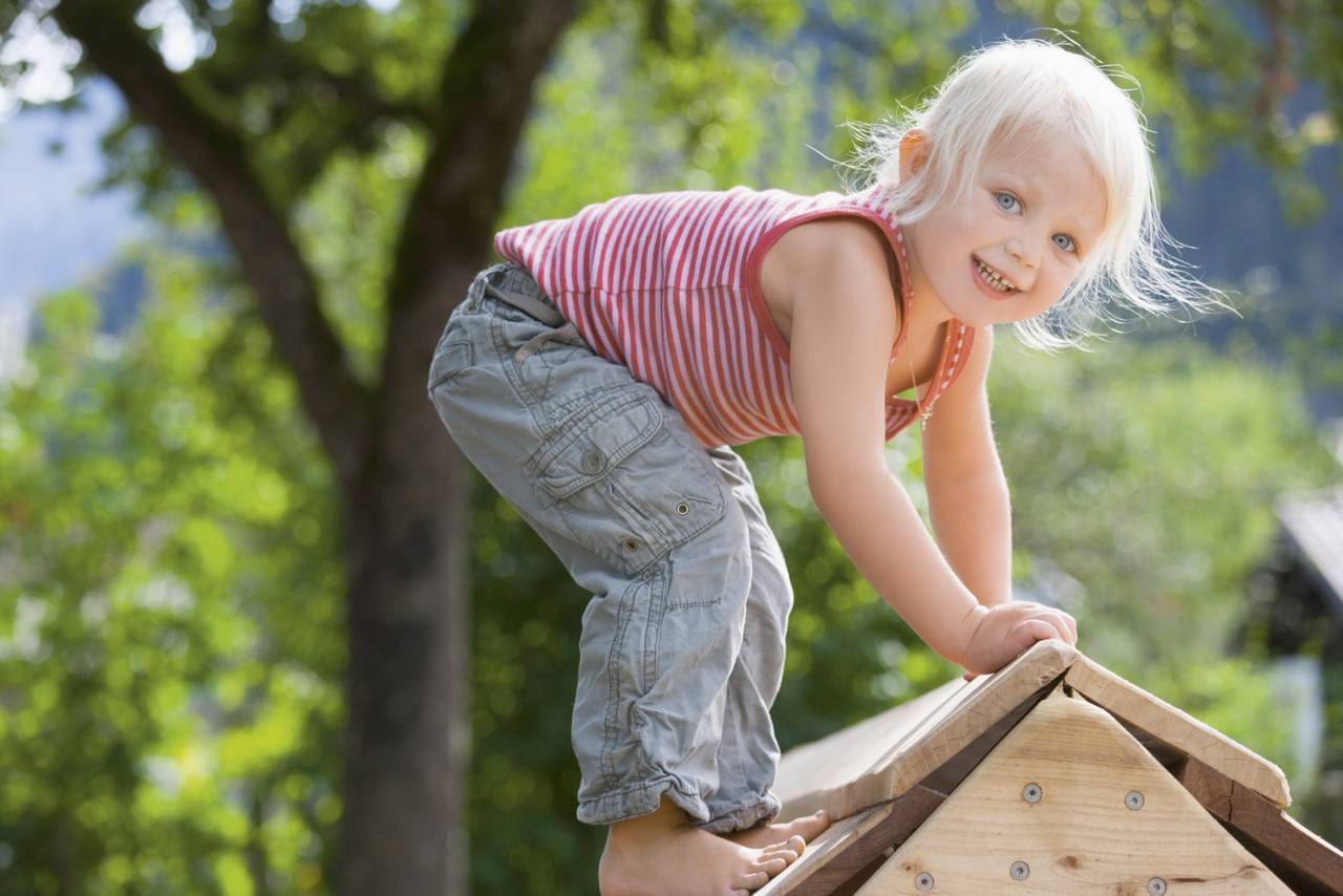 menina aventureira brincando de subir uma casinha