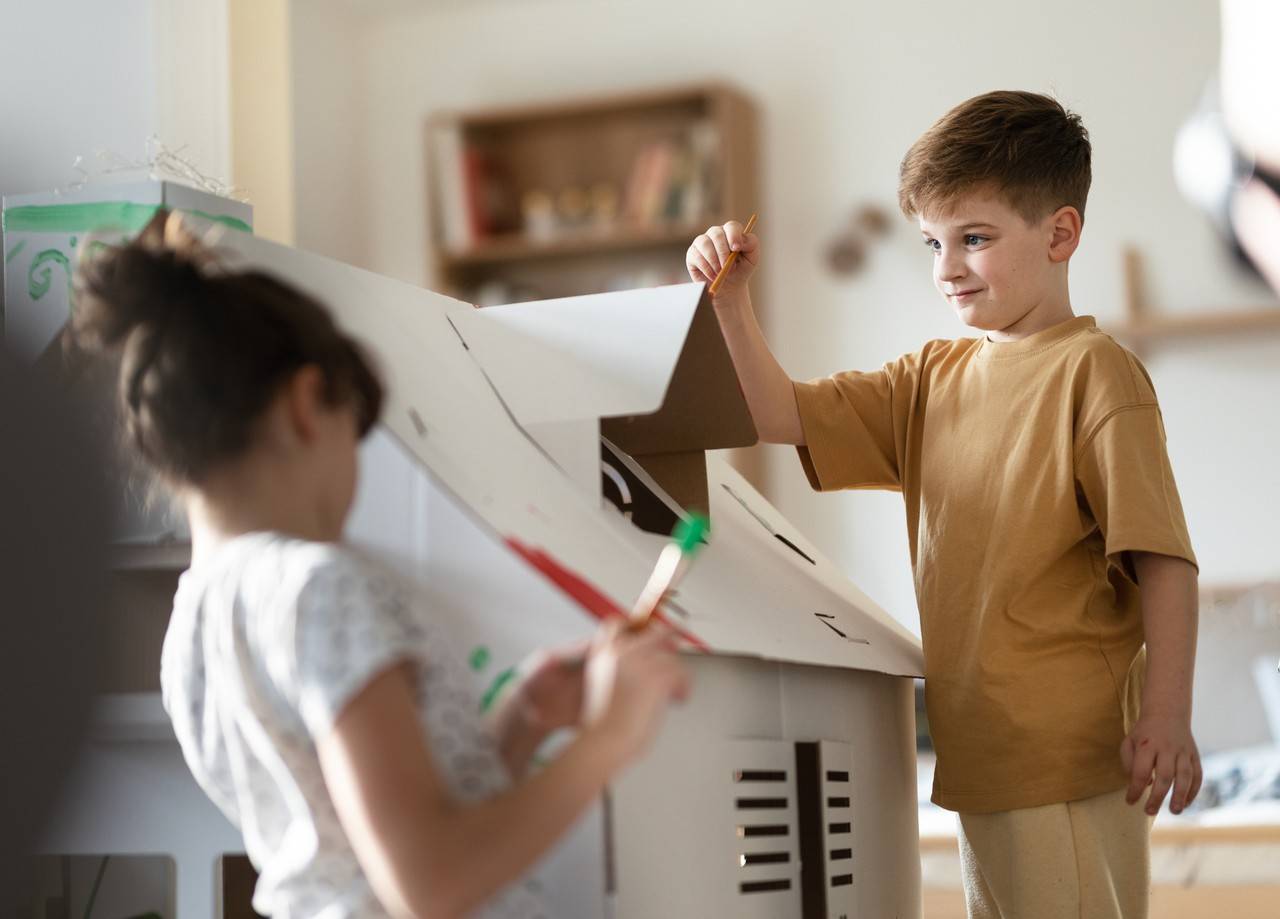 dois irmãos brincando com brinquedos não estruturados de papelão