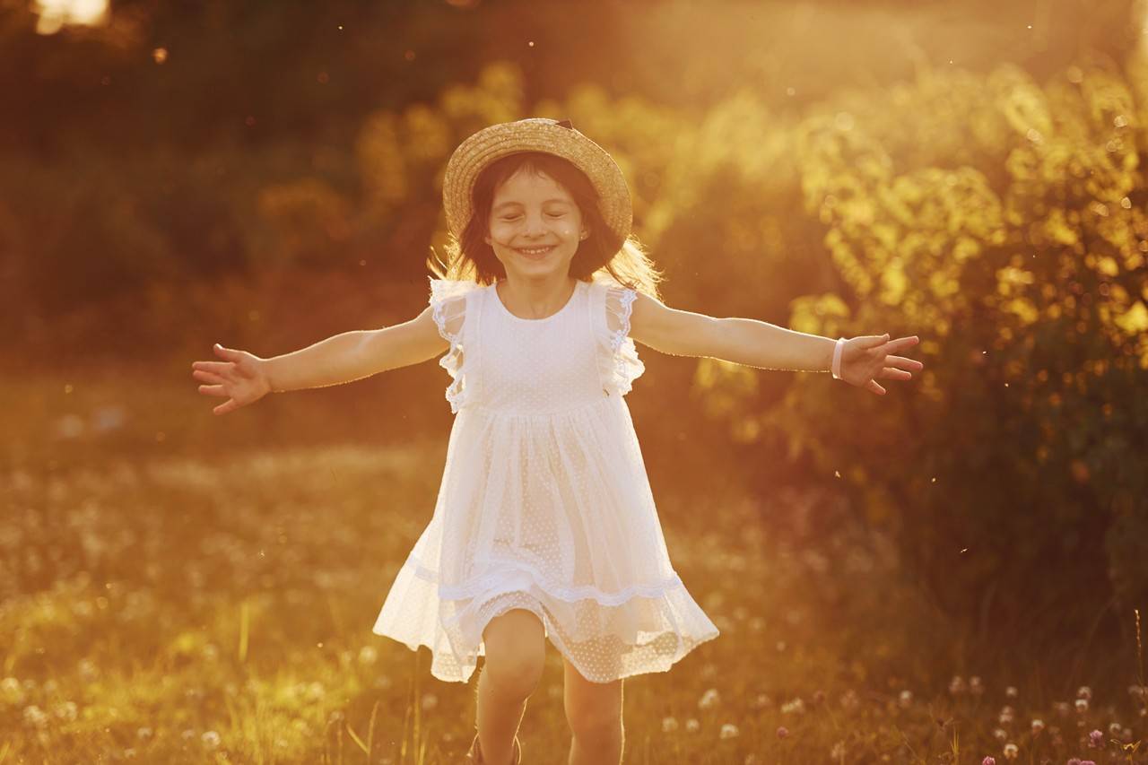 menina feliz de vestido branco se diverte ao ar livre