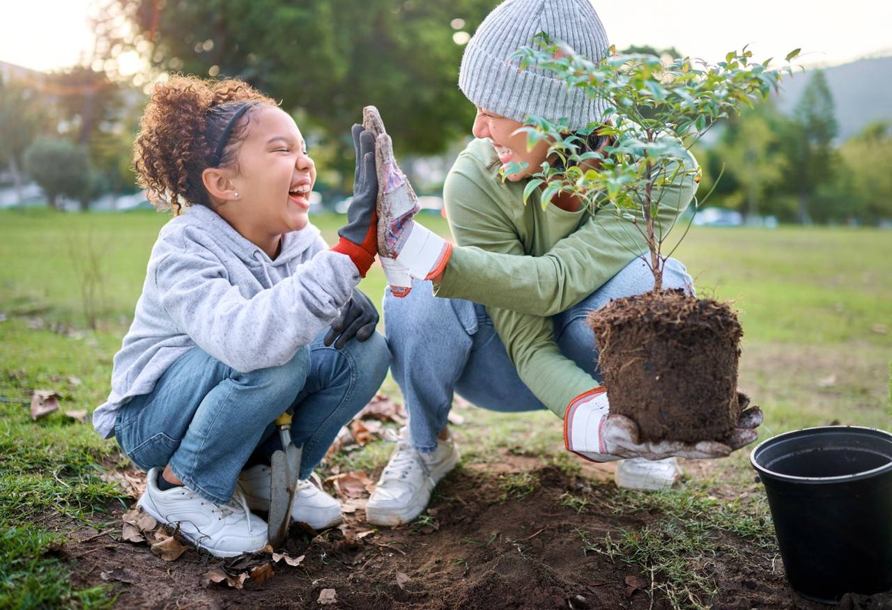 mãe e filha plantando uma árvore juntas bem felizes