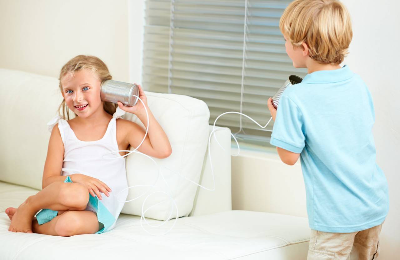 uma menina e um menino brincando de telefone sem fio