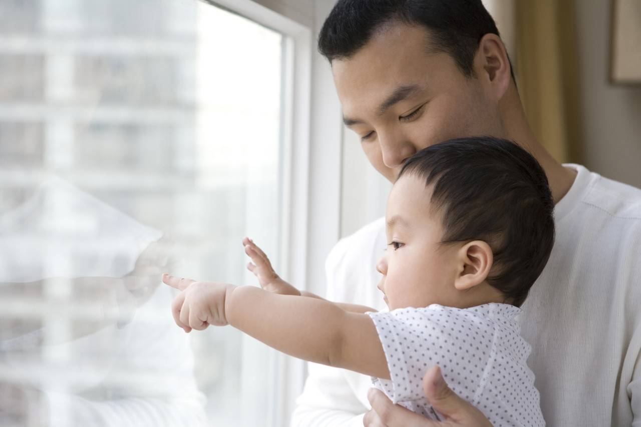 pai e filho asiáticos olhando pela janela