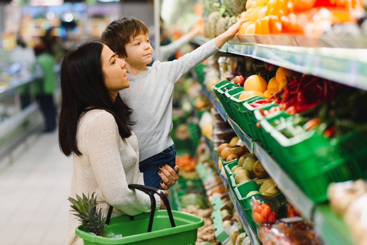 mãe e filho escolhendo frutas em uma quitanda