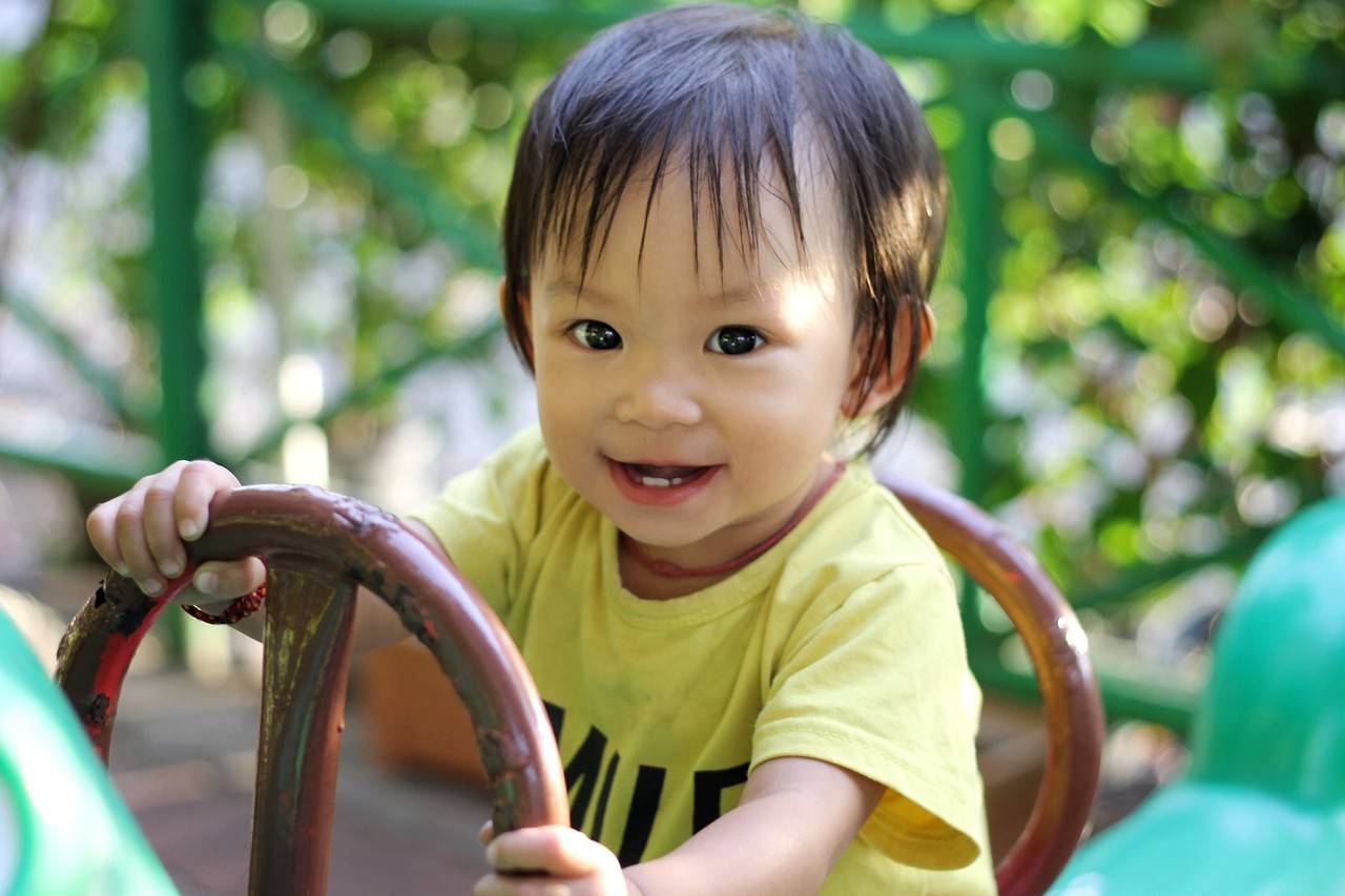 bebê asiático brincando com um carrinho de madeira
