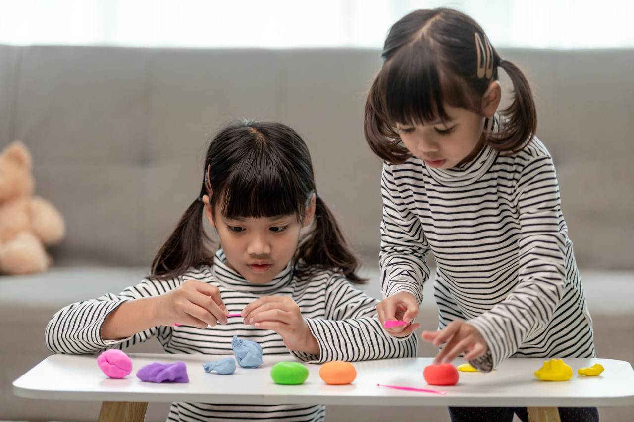 duas meninas pequenas brincando de massinhas