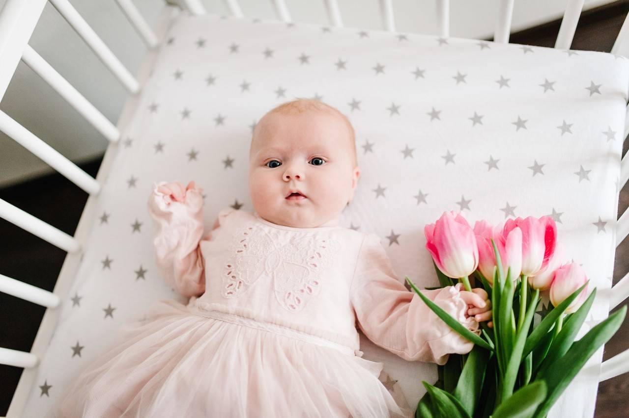 bebê deitada no berço com vestido rosa