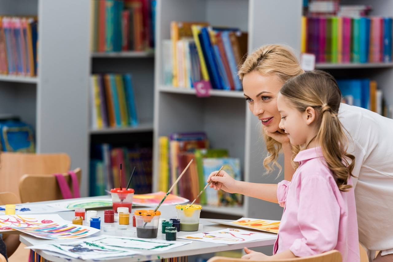 professor e criança pintando na biblioteca