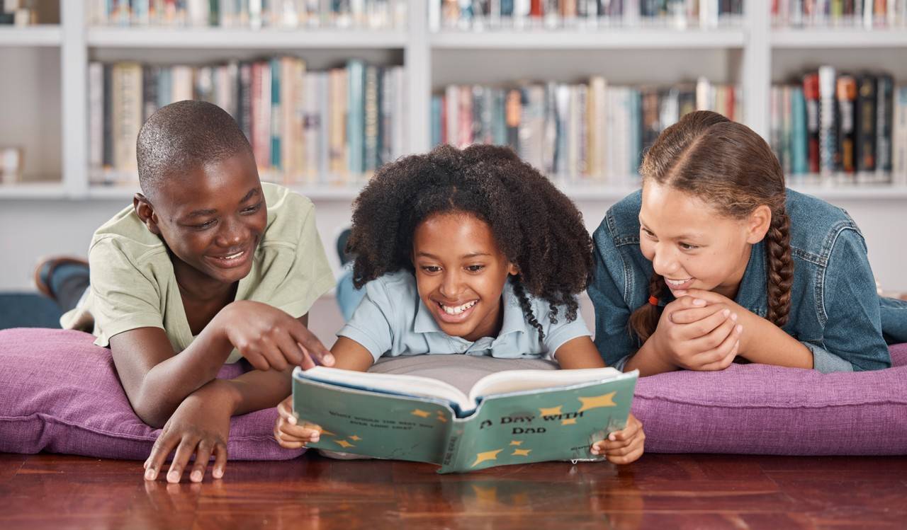 adolescentes deitados no chão de uma biblioteca caseira com um livro na mão