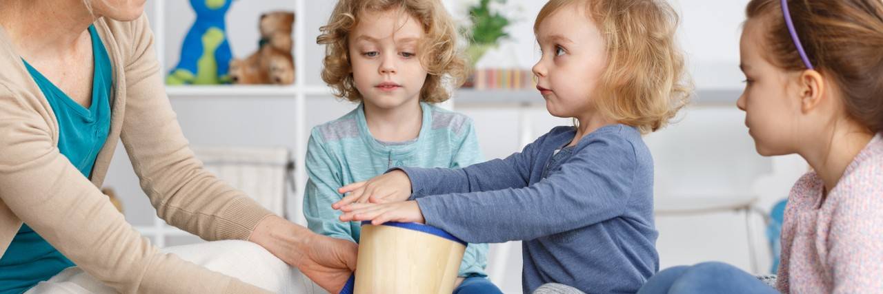 crianças brincando com um tambor feito com lata de leite