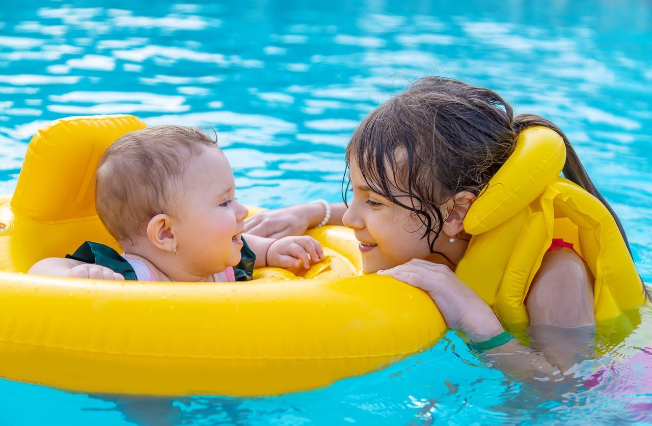 crianças brincando na piscina com boias 