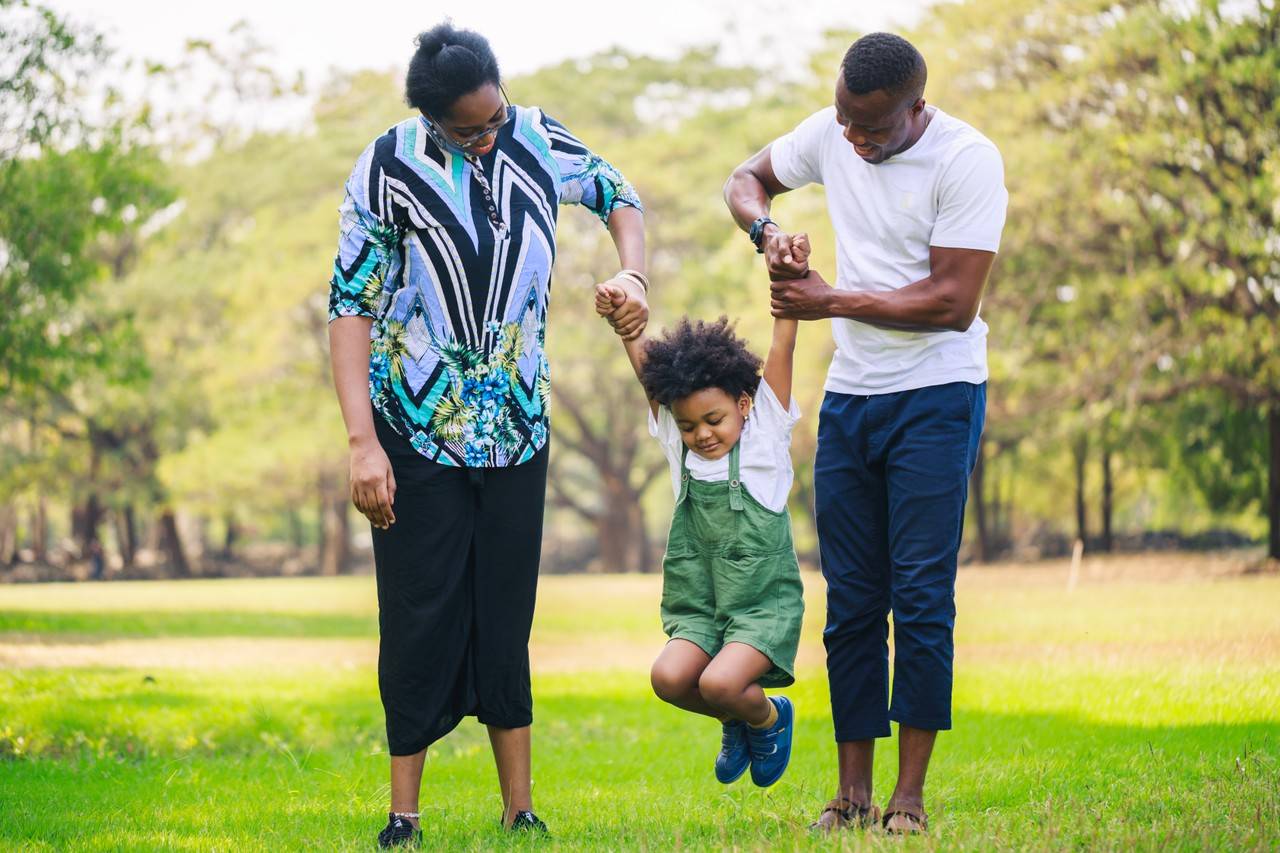 família unida passeando no parque com um menino usando tênis e um look estiloso